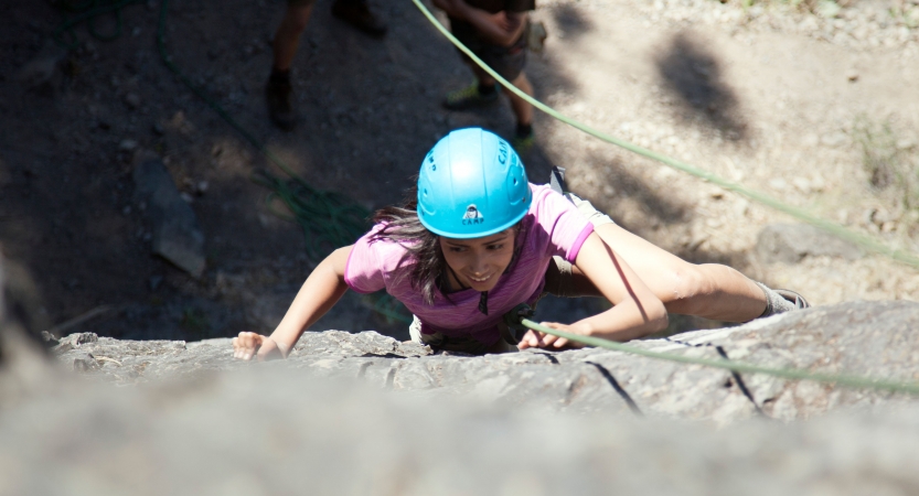 an outward bound student focuses while climbing a rock wall